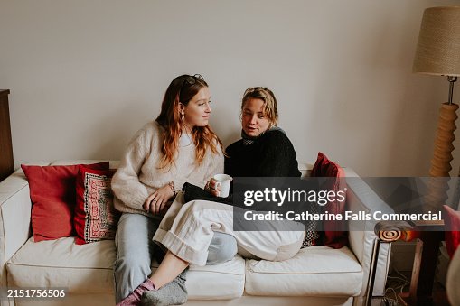 Two woman sit close together on a sofa having a serious discussion Two woman sit close together on a sofa having a serious discussion