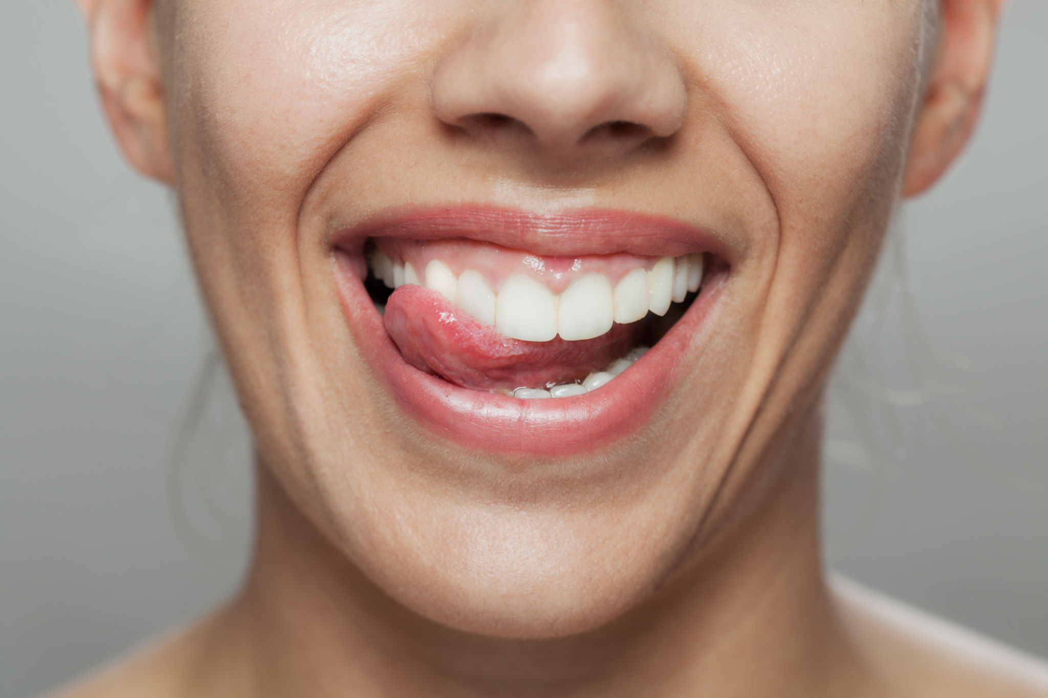Primer plano de una mujer alegre lamiéndose los labios, destacando la salud dental y la alegría Primer plano de una mujer alegre lamiéndose los labios, destacando la salud dental y la alegría