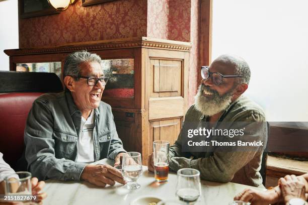 medium shot senior friends laughing together while relaxing in bar - amitié masculine photos et images de collection