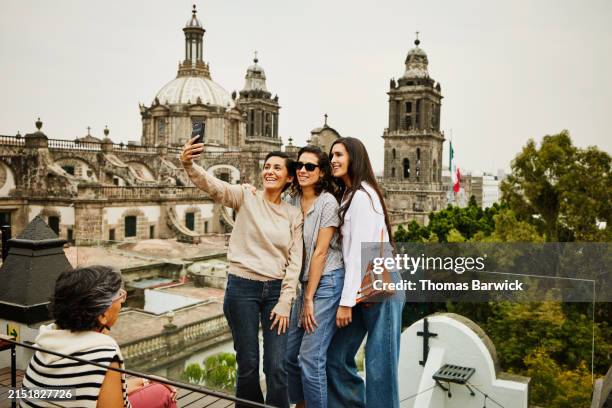 wide shot smiling female friends taking selfie at rooftop restaurant - cathédrale métropolitaine de mexico photos et images de collection