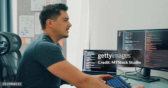Tired depressed bored man software developers using computer to write code application program for AI technology at desk with multiple screens work at home office. Programmer development. Tired depressed bored man software developers using computer to write code application program for AI technology at desk with multiple screens work at home office. Programmer development.