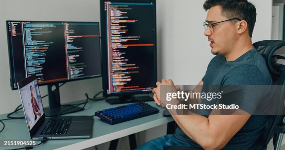 Young man software developers using computer to write code application program for AI technology and video call at desk with multiple screens work at home office. Programmer development. Young man software developers using computer to write code application program for AI technology and video call at desk with multiple screens work at home office. Programmer development.