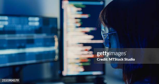 closeup asian woman software developers using computer to write code application program for ai technology at desk with multiple screens work at home office night. programmer development. - algemene verordening gegevensbescherming stockfoto's en -beelden