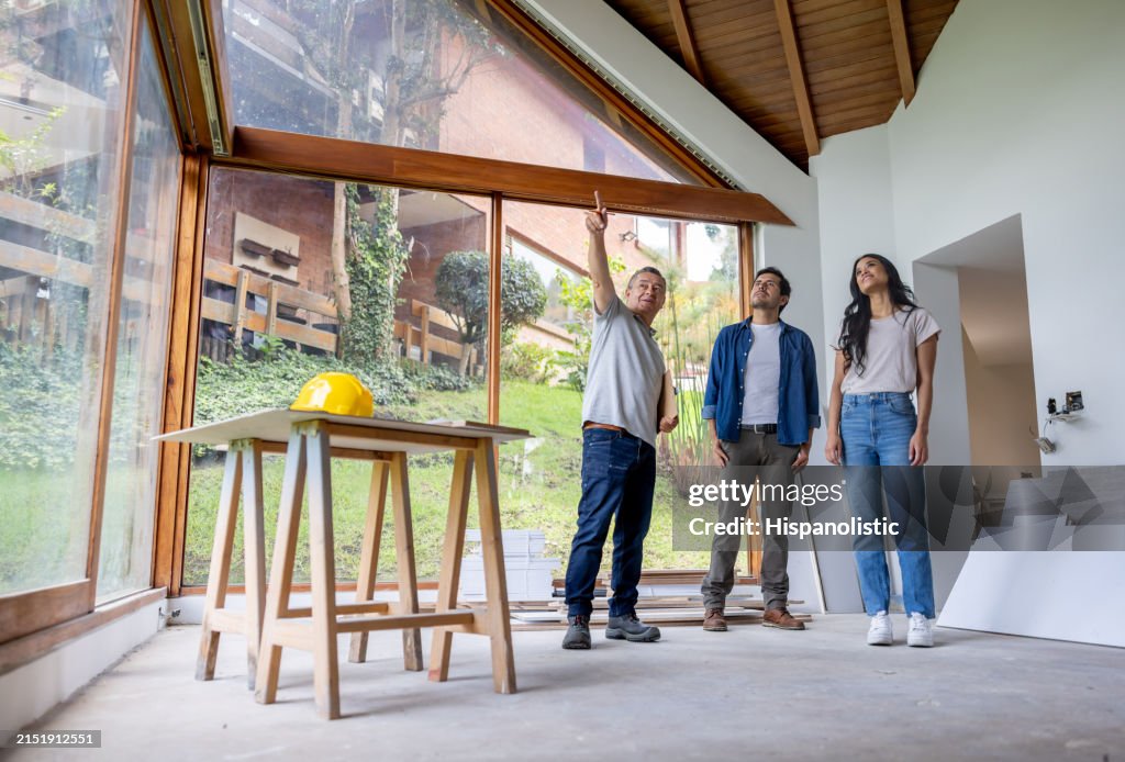 Un entrepreneur en construction discute avec des clients qui rénovent leur maison