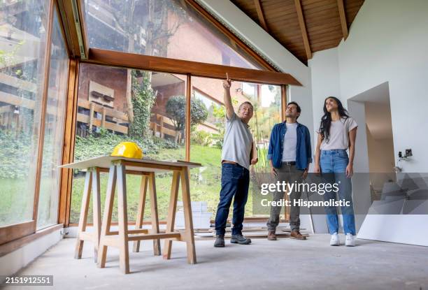 un entrepreneur en construction discute avec des clients qui rénovent leur maison - maison photos et images de collection