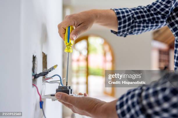 electricista instalando una toma de corriente mientras remodela una casa - electricista fotografías e imágenes de stock
