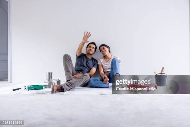 couple taking a break from painting their house - renovação de casa - fotografias e filmes do acervo