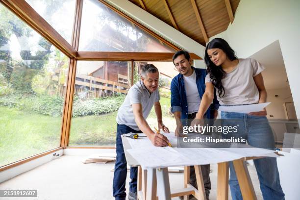 imprenditore edile che guarda i progetti con una coppia che ristruttura la propria casa - imprenditore edile foto e immagini stock