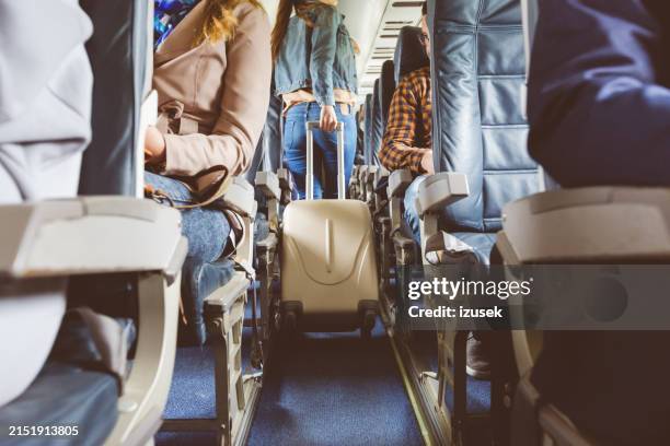 interior of airplane with people sitting on seats - vliegtuig stockfoto's en -beelden