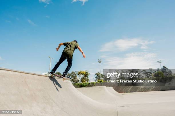 jeune homme faisant du skateboard au skatepark à l’extérieur - halfpipe photos et images de collection