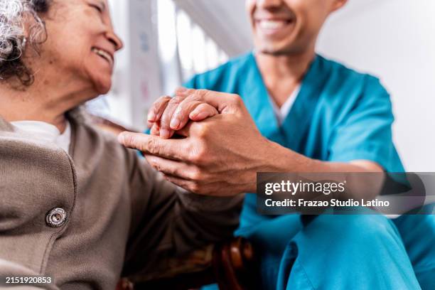 donna anziana che tiene le mani del caregiver a casa - infermiere foto e immagini stock