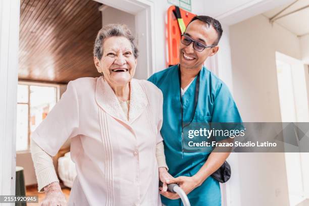 caregiver helping senior woman walk with walker at home - fragility stock pictures, royalty-free photos & images