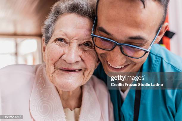 portrait of a senior woman embracing caregiver at home - cuidados paliativos fotografías e imágenes de stock