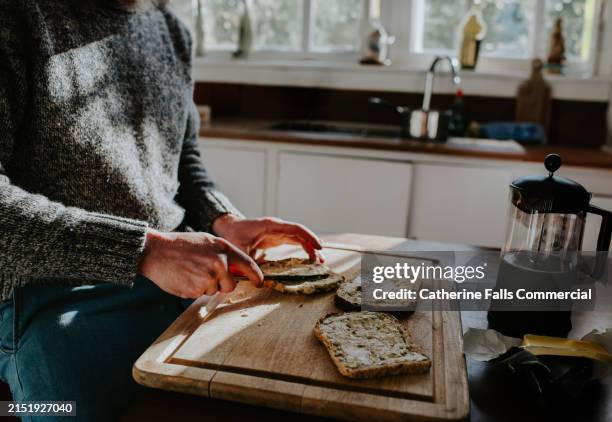 a man spreads butter onto lightly toasted bread in a domestic kitchen - margarina fotografías e imágenes de stock