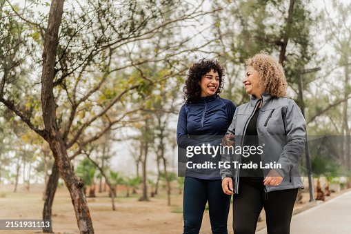 Madre e figlia che parlano mentre camminano nel parco pubblico Madre e figlia che parlano mentre camminano nel parco pubblico