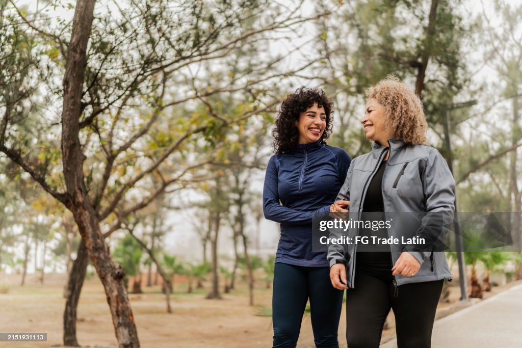 Mother and daughter talking while walking through the public park