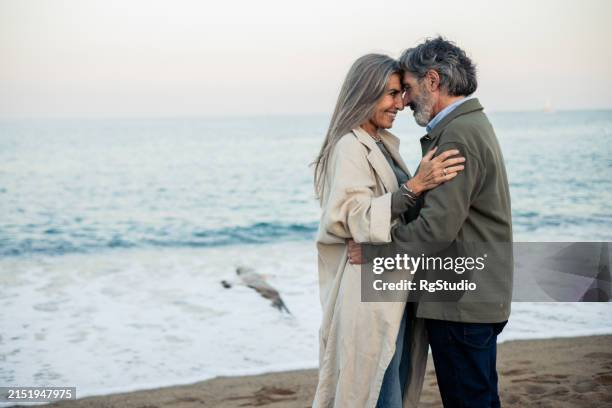 happy mature couple enjoying their love by the sea - beautiful people stock pictures, royalty-free photos & images
