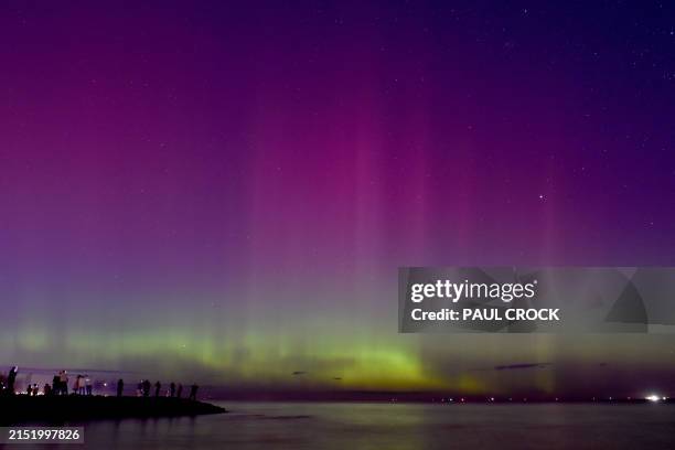 People watch the the aurora australis or southern lights caused by a solar storm at Port Phillip Bay in Melbourne on May 11, 2024.