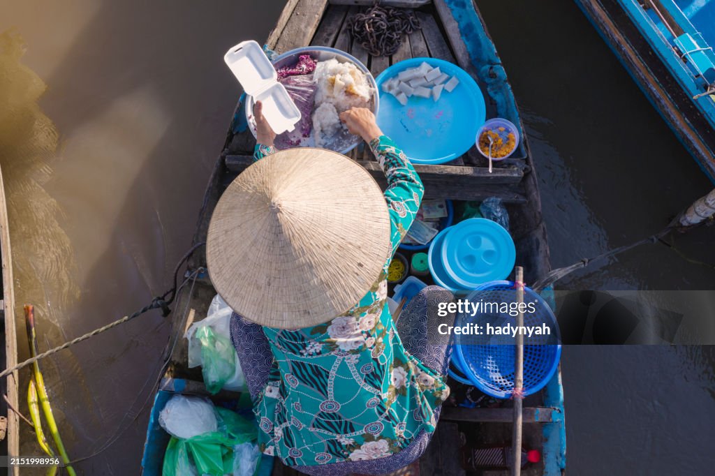 Vietnamese woman preparing coconut's snacks, floating market, Mekong River Delta, Vietnam