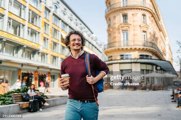 joven bebiendo café para llevar mientras camina por la calle en parís en francia - saint denis parís fotografías e imágenes de stock