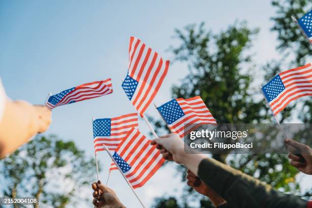 a group of people is waving small american flags at sunset - bandeira dos estados unidos da américa imagens e fotografias de stock