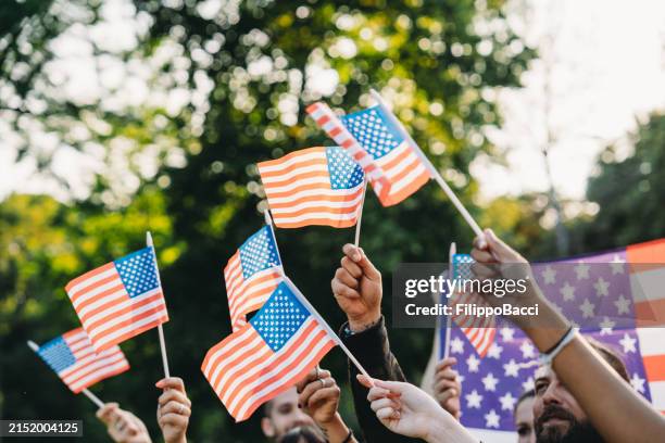 a group of people is waving small american flags at sunset - feriado americano memorial day imagens e fotografias de stock