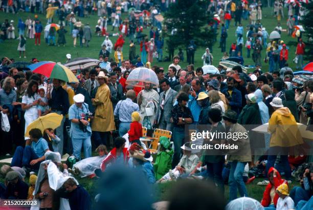 July 1976 - 1976 Montreal Summer Olympics - Equestrian, Eventing - HRH Queen Elizabeth II stands beneath an umbrella to shelter from the rain.