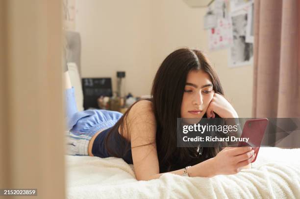 teenage girl lying on her bed and using a smart phone - générique photos et images de collection