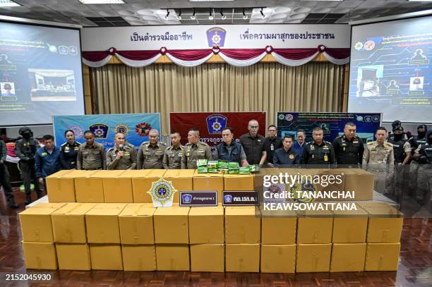 Acting Thai National Police Chief Kittharath Punpetch and Deputy Prime Minister Anutin Charnvirakul stand alongside other officials in front of boxes...