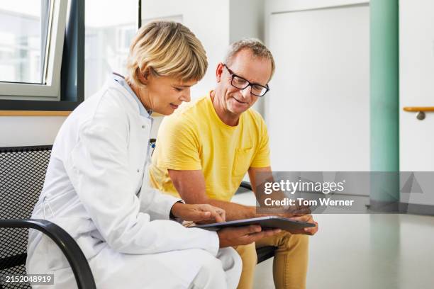 female doctor and senior patient discussing health plan using digital tablet - ärztliche untersuchung stock-fotos und bilder