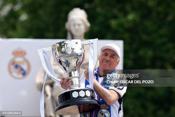 Real Madrid's Italian coach Carlo Ancelotti holds their 36th La Liga trophy as Real Madrid players parade onboard a bus to celebrate at the Cibeles...