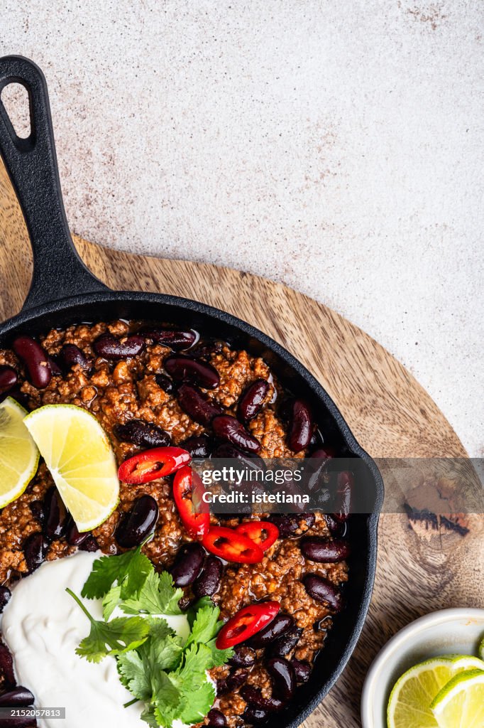 Chili con carne in cast iron pan served with lime, sour cream