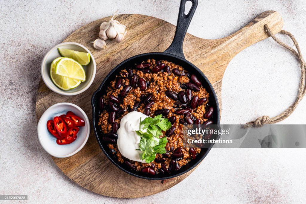 Chili con carne in cast iron pan served with lime, sour cream