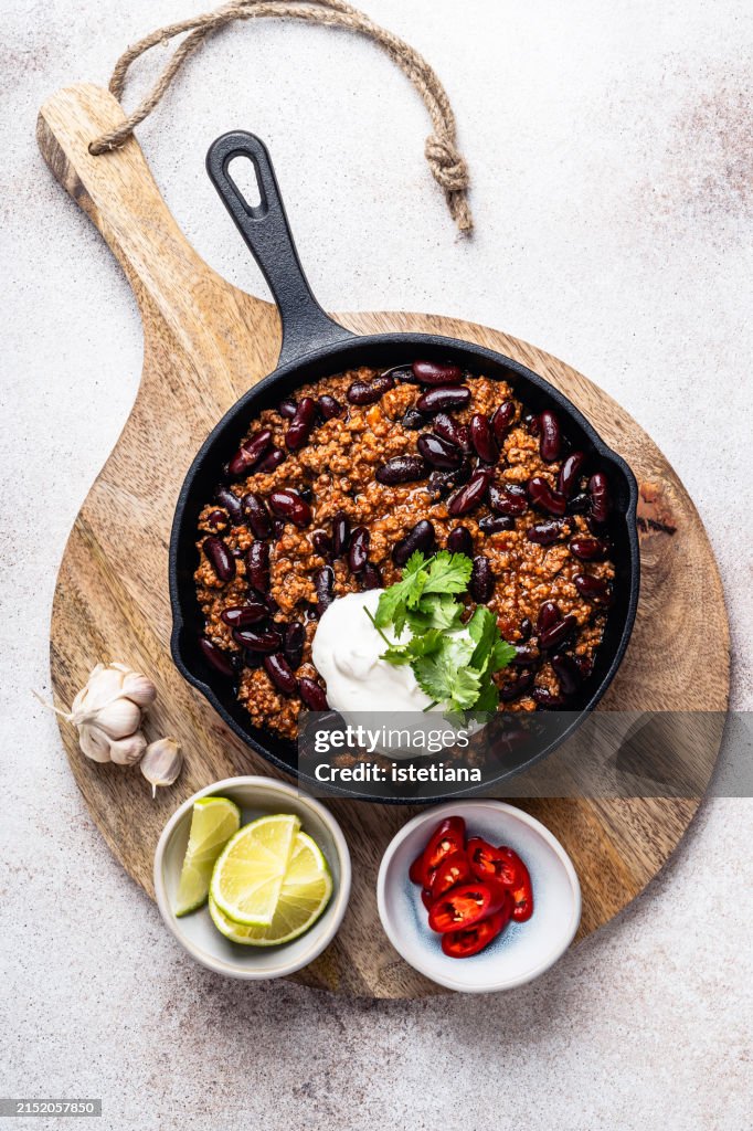 Chili con carne in cast iron pan served with lime, sour cream