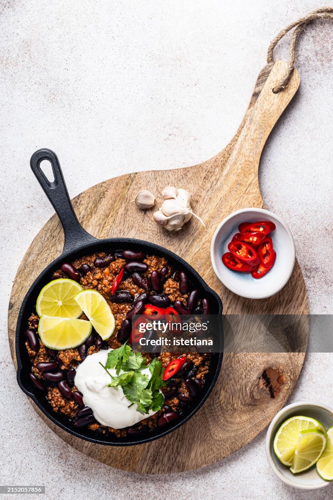 Chili con carne in cast iron pan served with lime, sour cream