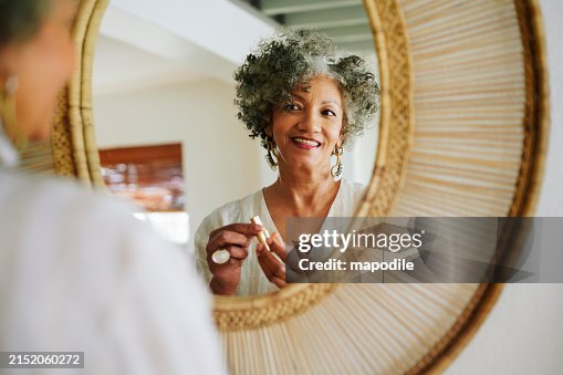 Donna matura sorridente che indossa il rossetto in uno specchio a casa Donna matura sorridente che indossa il rossetto in uno specchio a casa