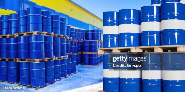 Warehouse of chemical products. Pallets with barrels in open air. Metal tanks for chemical liquids. Storage area. Barrels with chemicals near hangars. Fuel warehouse under blue sky. Chemical industry