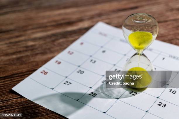 calendar and hourglass on the table - verval stockfoto's en -beelden