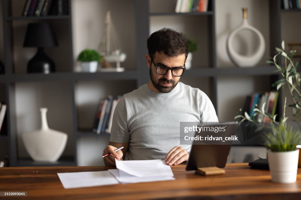 A serious male remote online manager discussing current issues with his coworkers through a video call on his tablet.
