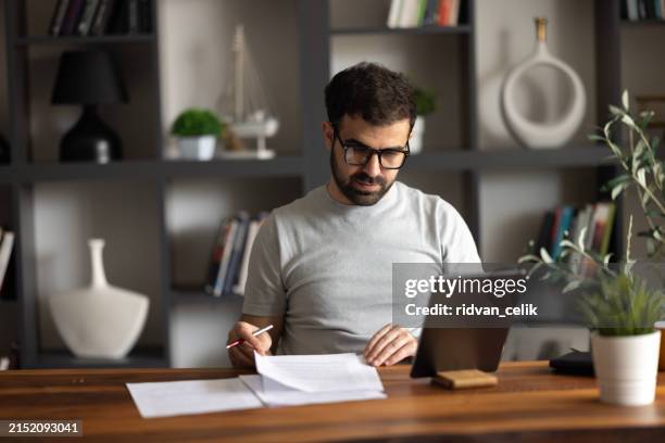 a serious male remote online manager discussing current issues with his coworkers through a video call on his tablet. - file sharing stock pictures, royalty-free photos & images
