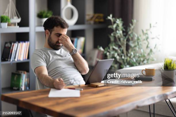 mann überarbeiteter freiberufler zu hause halten augen anstrengung schmerzen - mitarbeiterbindung stock-fotos und bilder