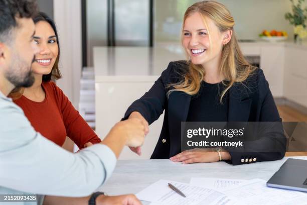 real estate or insurance agent or lawyer shaking hands with couple. they are signing home loan mortgage or contract documents. - lease agreement stock pictures, royalty-free photos & images