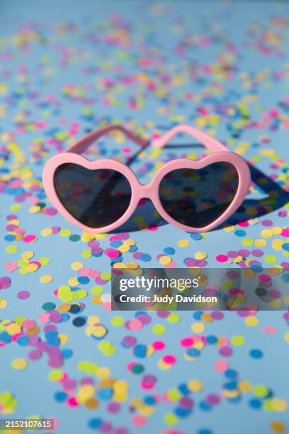 heart shaped sunglasses on confetti - scherzartikel stock-fotos und bilder