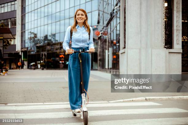 donna che guida il monopattino elettrico in fondo alla città urbana - monopattino foto e immagini stock