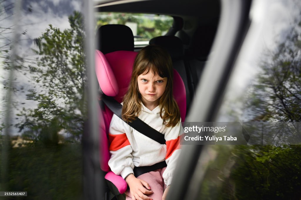Enfant faisant la grimace à l’intérieur d’une voiture.
