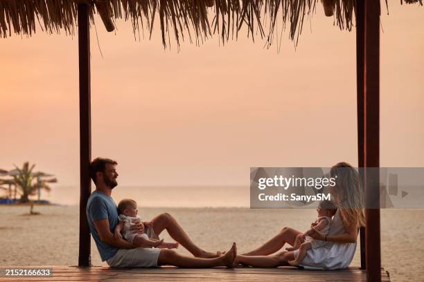 beautiful family at tropical paradise beach during sunset - twin stock pictures, royalty-free photos & images