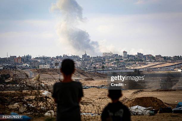 Boys watch smoke billowing during Israeli strikes east of Rafah in the southern Gaza Strip on May 13 amid the ongoing conflict between Israel and the...