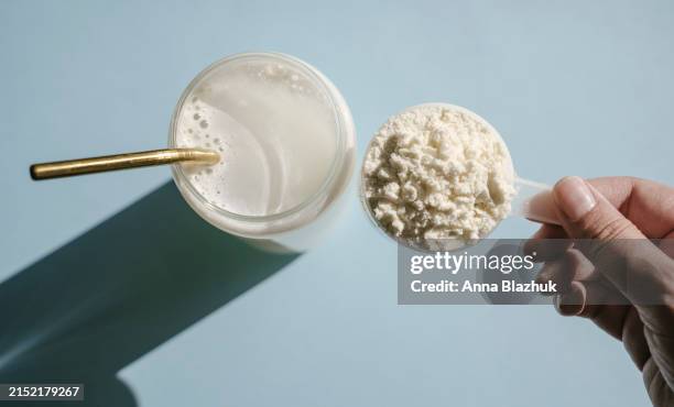 protein isolate powder. unflavored whey protein in measuring scoop and drinking glass in bright sunlight - proteïnedrank stockfoto's en -beelden