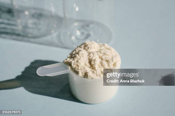 protein isolate powder. unflavored whey protein in measuring scoop in bright sunlight - cucchiaio dosatore foto e immagini stock