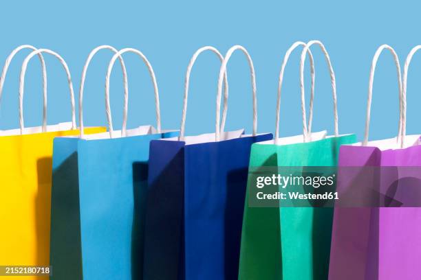colorful paper bags against blue background - bärkasse bildbanksfoton och bilder